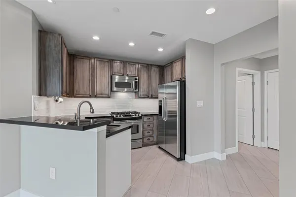 a kitchen with stainless steel appliances granite countertop a refrigerator stove and sink