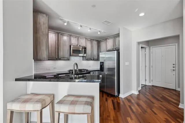a kitchen with kitchen island granite countertop a sink cabinets and stainless steel appliances