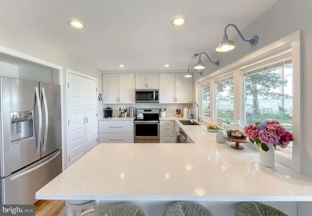 a kitchen with granite countertop a refrigerator a sink dishwasher a oven with white cabinets and wooden floor