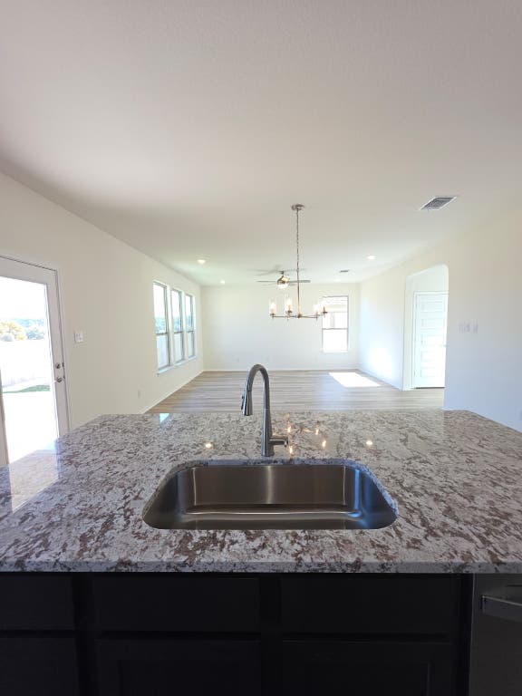 1609 Red Berry Pass Georgetown, TX 78628 - Photo 29 of 29 a kitchen with kitchen island granite countertop a sink stainless steel appliances refrigerator and window