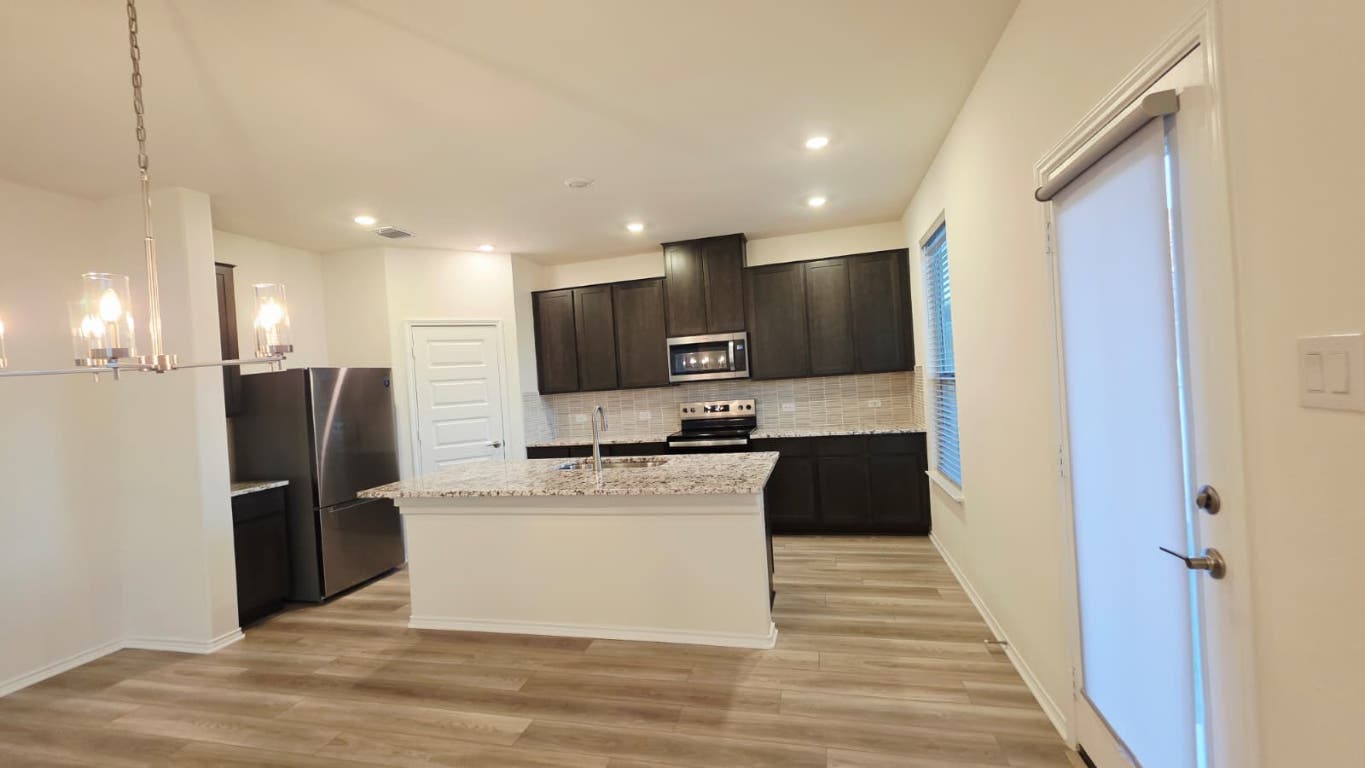 1609 Red Berry Pass Georgetown, TX 78628 - Photo 21 of 29 a kitchen with kitchen island stainless steel appliances cabinets and a counter top space