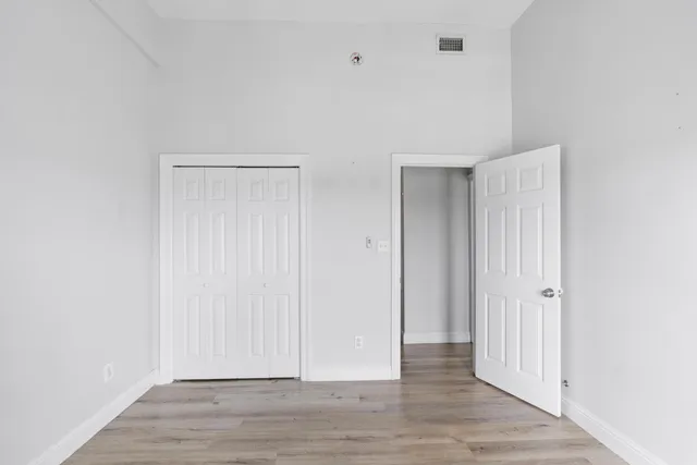 an empty room with wooden floor fan and windows