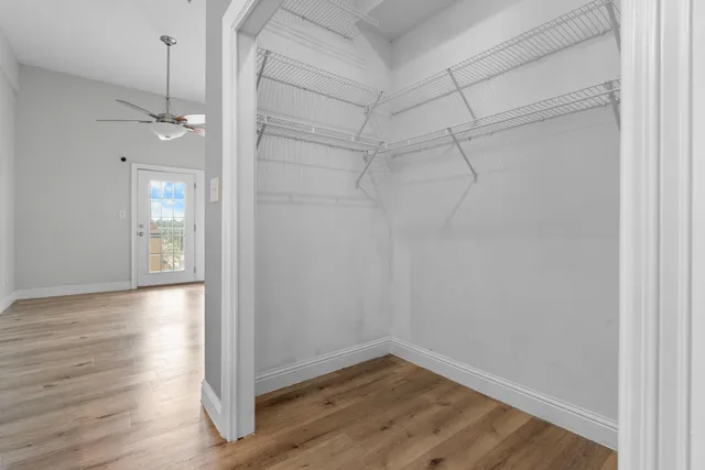 a view of empty room with wooden floor and fan