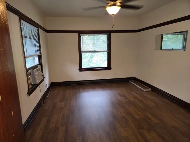 a view of an empty room with wooden floor and a window