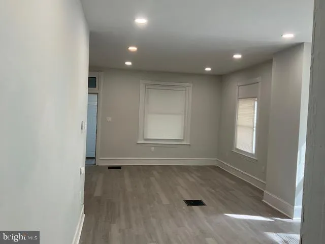 an empty room with wooden floor and windows