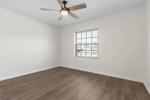 an empty room with wooden floor fan and windows