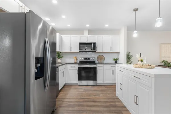 a kitchen with stainless steel appliances granite countertop a refrigerator a stove and a sink