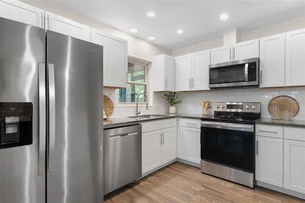 a kitchen with stainless steel appliances granite countertop a stove a sink and a refrigerator