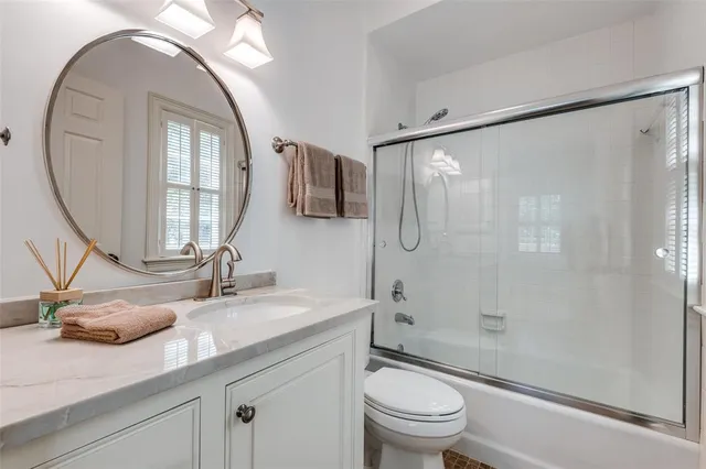a bathroom with a granite countertop sink a toilet and shower