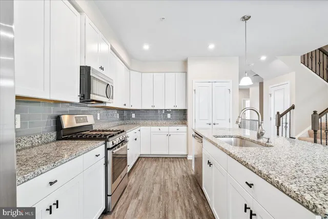 a large kitchen with granite countertop a sink a counter space appliances and cabinets