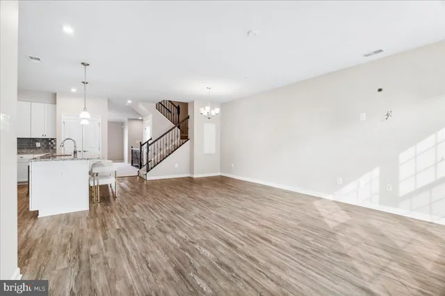 a view of empty room with wooden floor and kitchen view