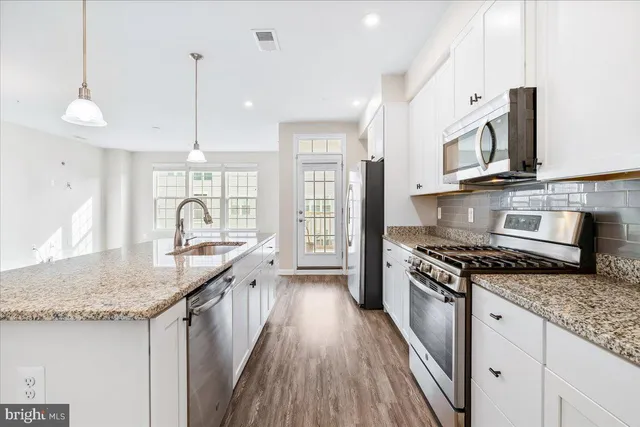 a kitchen with stainless steel appliances granite countertop a stove a sink and a microwave