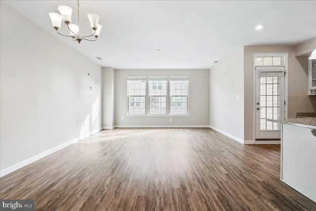 an empty room with wooden floor chandelier fan and windows