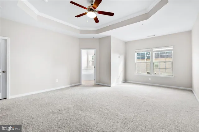 an empty room with chandelier fan and windows