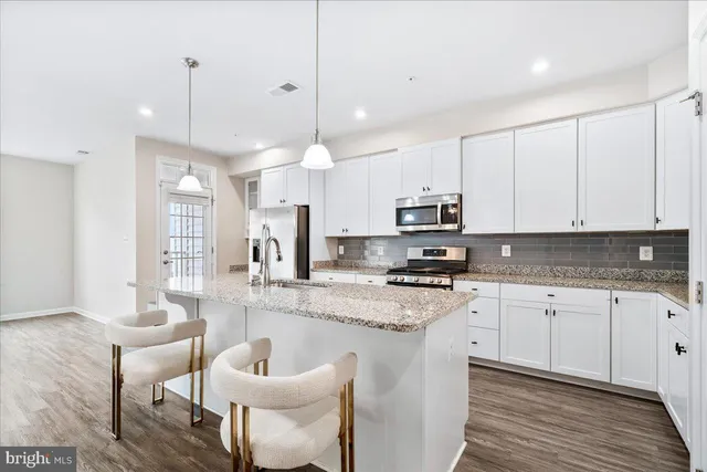 a large kitchen with stainless steel appliances kitchen island granite countertop a sink a stove a dining table and chairs