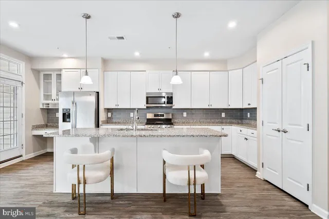 a kitchen with kitchen island granite countertop a table chairs refrigerator and microwave