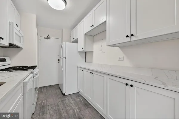 a kitchen with white cabinets and wooden floor
