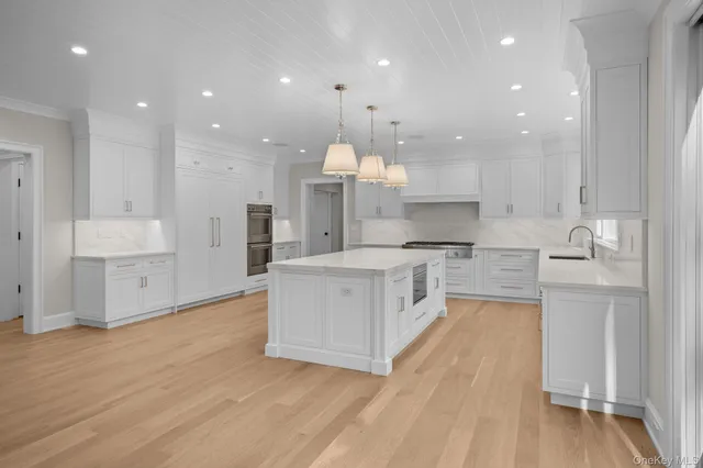 a large kitchen with stainless steel appliances kitchen island granite countertop a large counter top and a stove top oven