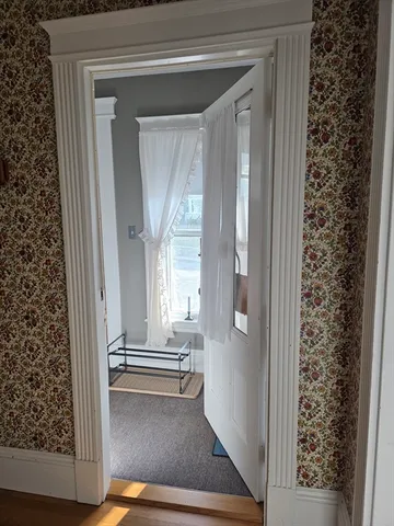 a view of a hallway to a livingroom with wooden floor and a fireplace