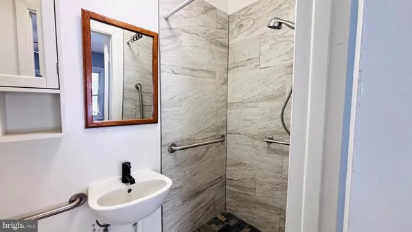 a bathroom with a sink and mirror with shower