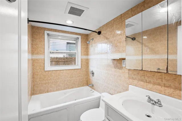 a bathroom with a bathtub shower sink vanity and toilet