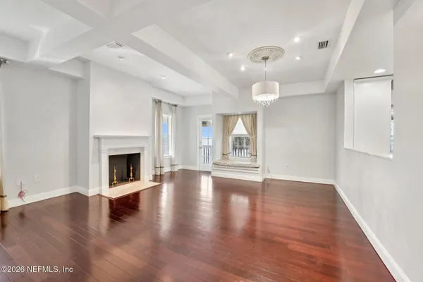 a view of an empty room with wooden floor fireplace and a window