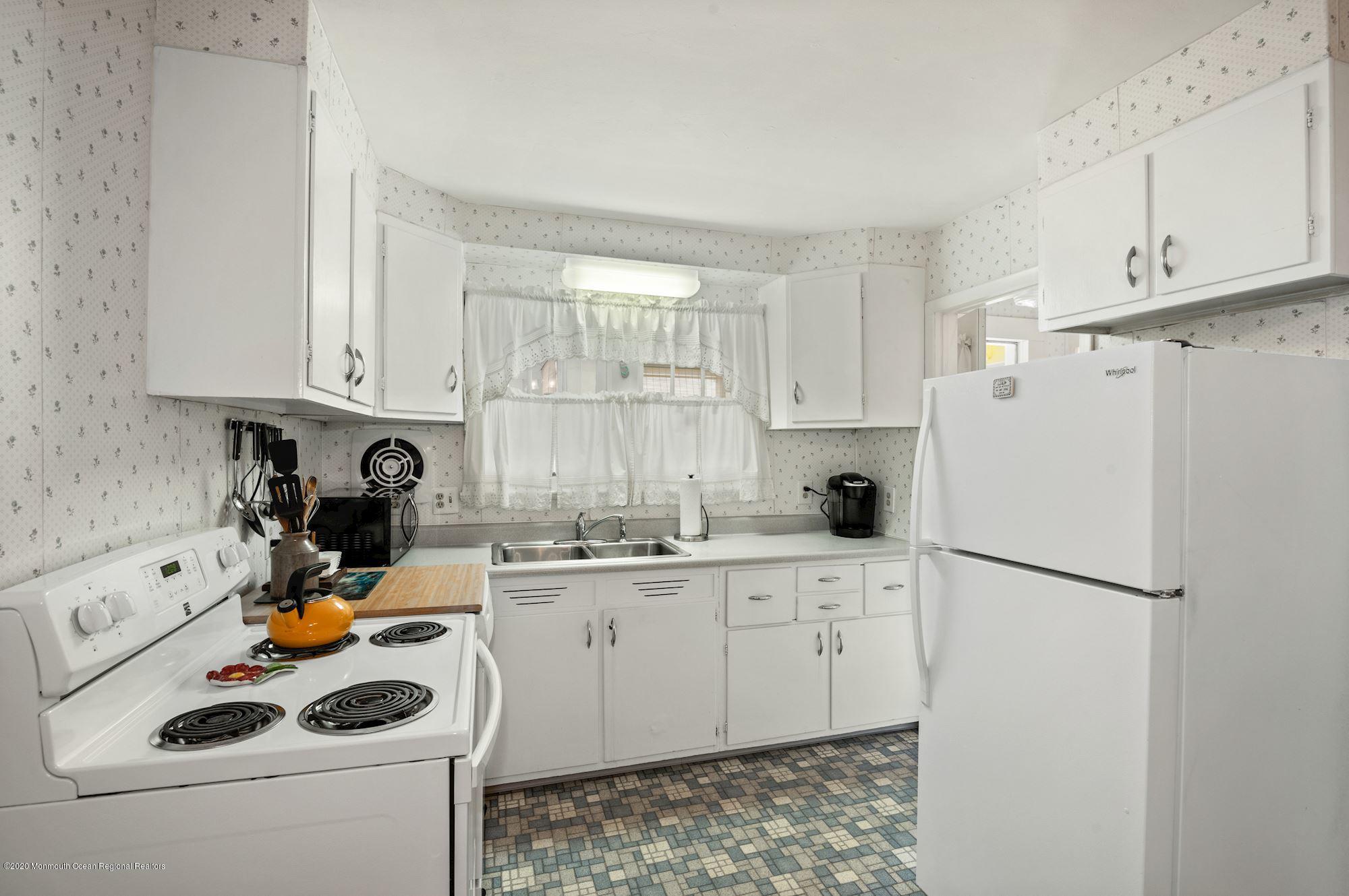306 Cedar Road Point Pleasant, NJ 08742 - Photo 4 of 28 a kitchen with a sink a refrigerator and white cabinets