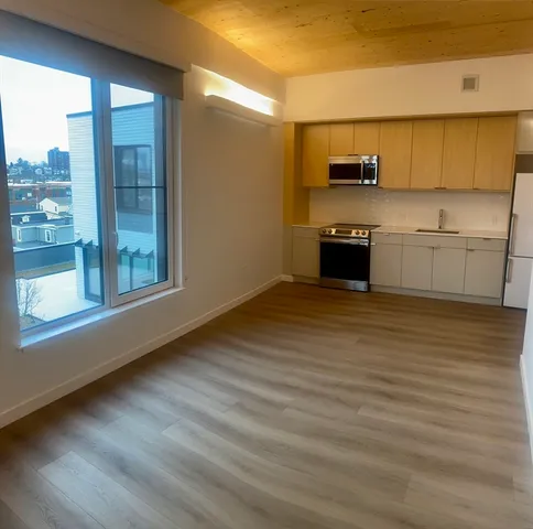 a view of a kitchen with stainless steel appliances wooden floor and cabinets
