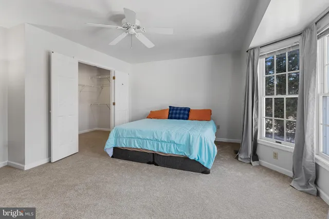 a bedroom with a large bed and a chandelier fan