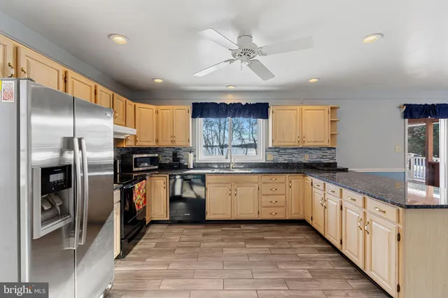 a kitchen with stainless steel appliances granite countertop a refrigerator a sink and white cabinets