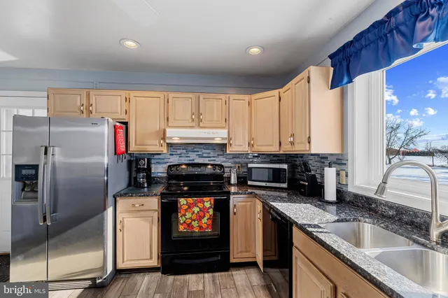 a kitchen with stainless steel appliances granite countertop a sink stove and refrigerator