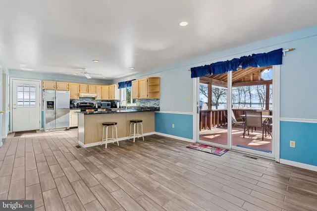 a kitchen with stainless steel appliances kitchen island granite countertop a table chairs cabinets and wooden floor