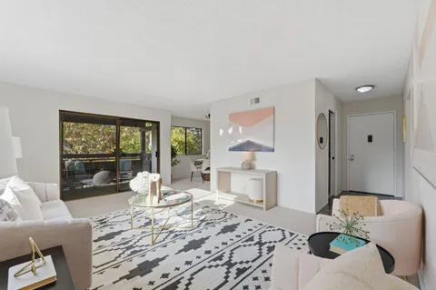 a living room with furniture large window and wooden floor