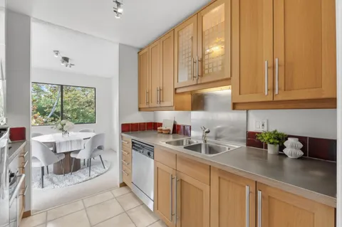a kitchen with stainless steel appliances granite countertop a sink a stove and white cabinets