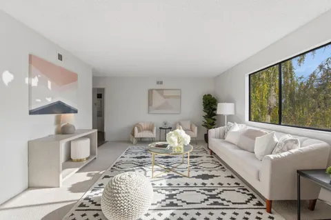 a living room with furniture wooden floor and a large window