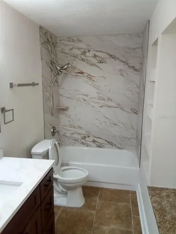 a bathroom with a granite countertop toilet sink and shower