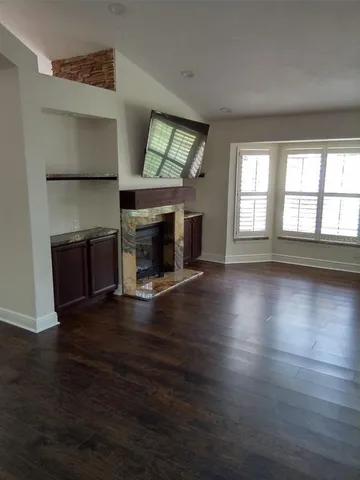 an empty room with wooden floor fireplace and windows