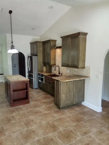 a kitchen with stainless steel appliances granite countertop a sink and a refrigerator