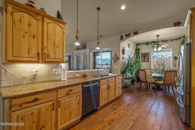 a kitchen with stainless steel appliances granite countertop wooden floors wooden cabinets a dining table and chairs