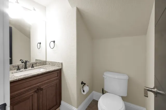 a bathroom with a granite countertop toilet sink and mirror