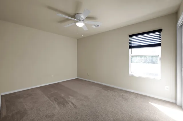 an empty room with a fan & a window
