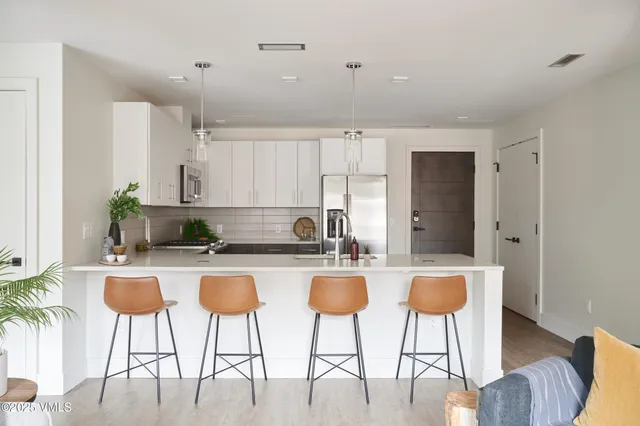 a kitchen with stainless steel appliances granite countertop a stove a refrigerator a white table and chairs with wooden floor