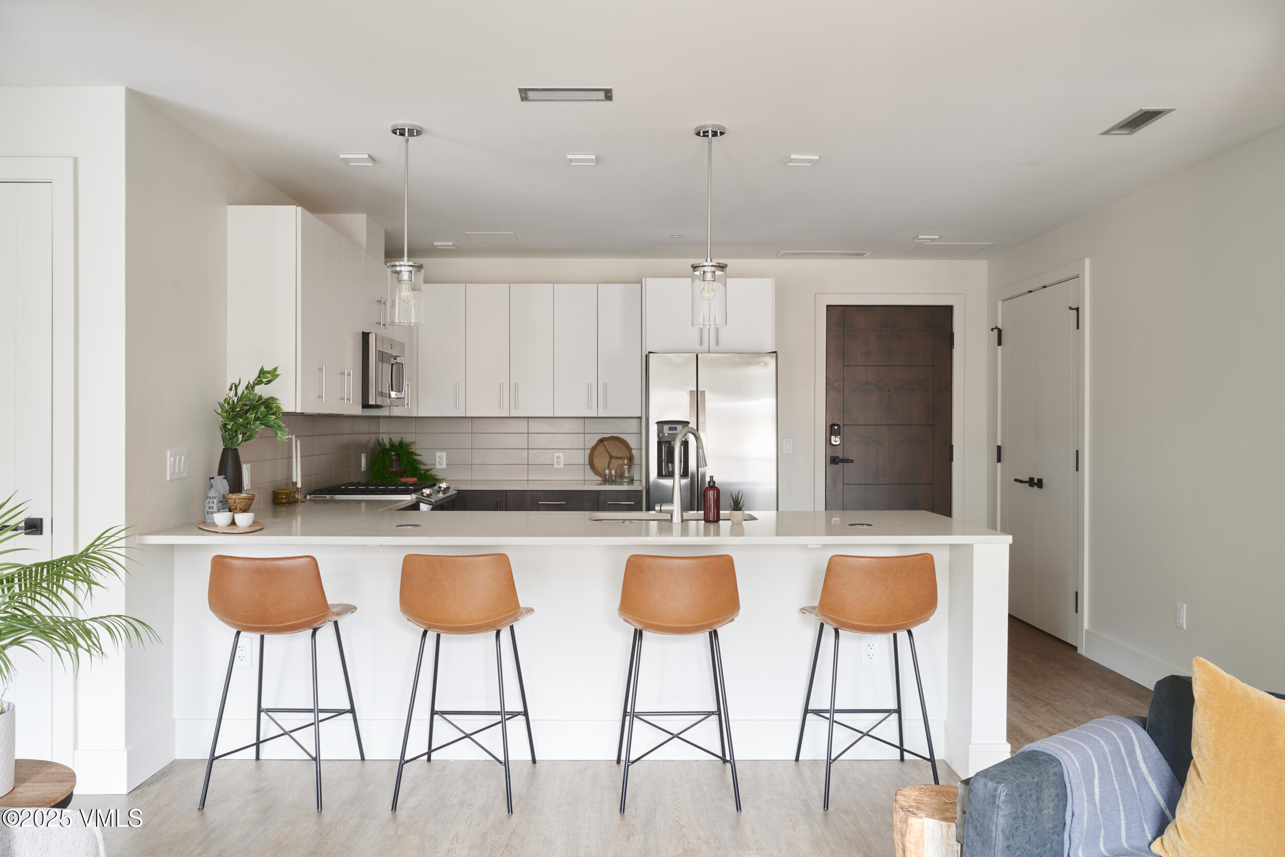 a kitchen with stainless steel appliances granite countertop a stove a refrigerator a white table and chairs with wooden floor