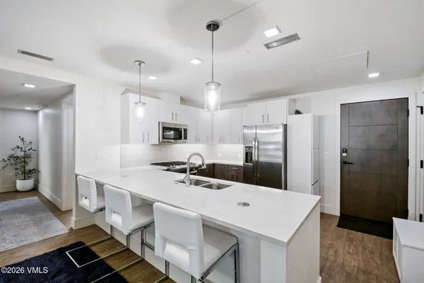 a kitchen with stainless steel appliances granite countertop a stove a refrigerator a white table and chairs with wooden floor