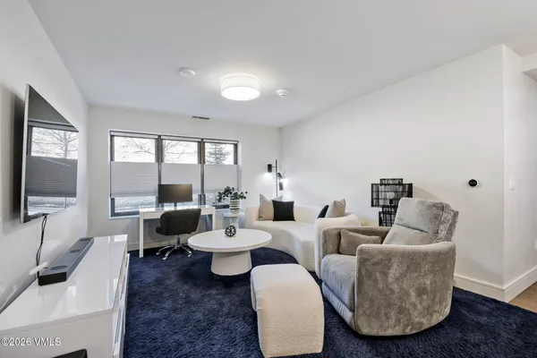 a living room with furniture a wooden floor and kitchen view