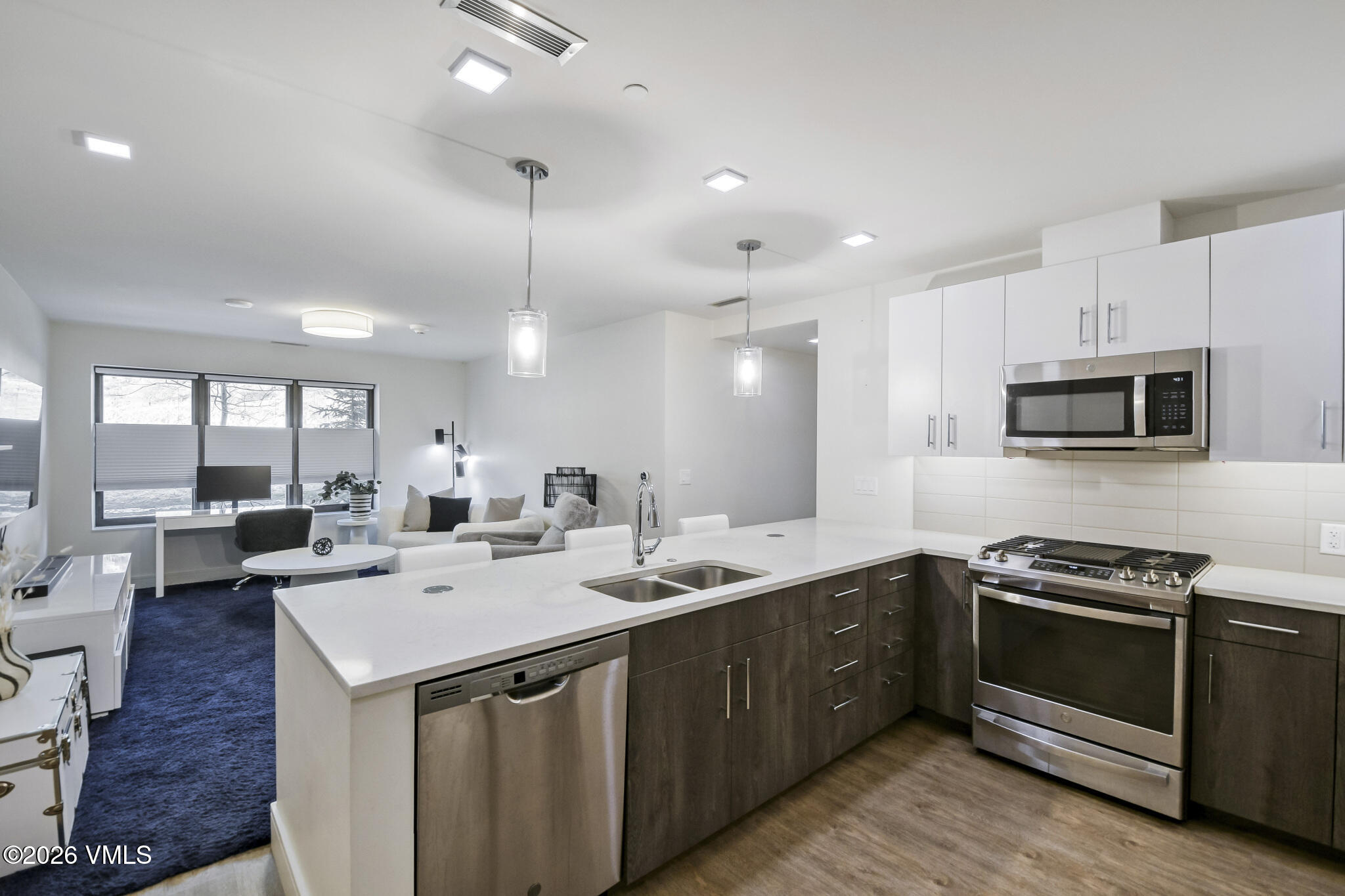 430 South Frontage Road East, Unit RUD Vail, CO 81657 - Photo 9 of 30 a kitchen with stainless steel appliances a sink a stove a microwave a center island and living room view