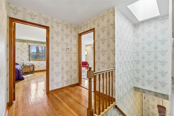 a view of a hallway with wooden floor and dining room view