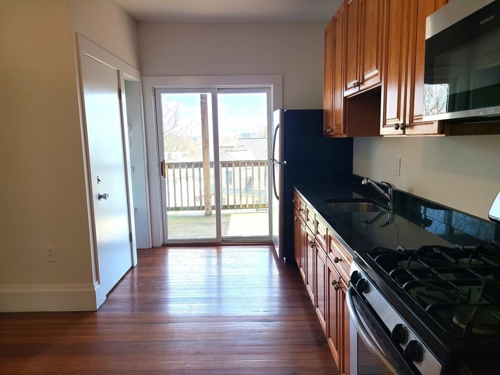 27 Buttonwood Street, Unit 3 Boston, MA 02125 - Photo 17 of 22 a kitchen with granite countertop a stove and a wooden floor