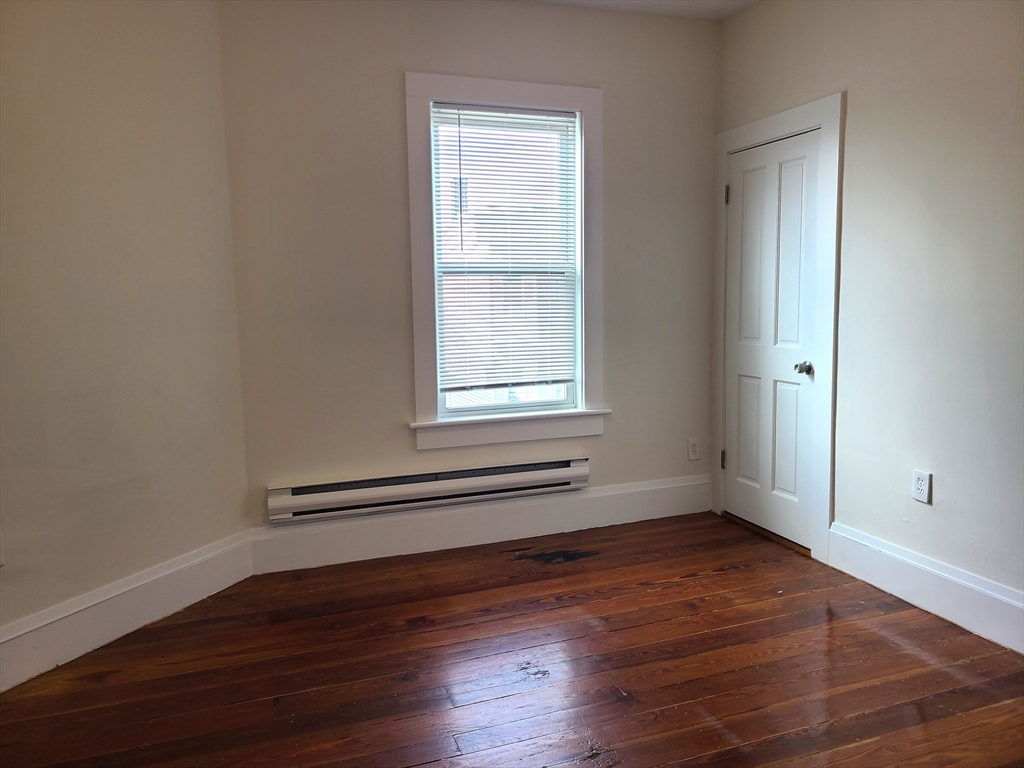 27 Buttonwood Street, Unit 3 Boston, MA 02125 - Photo 10 of 22 an empty room with wooden floor and windows