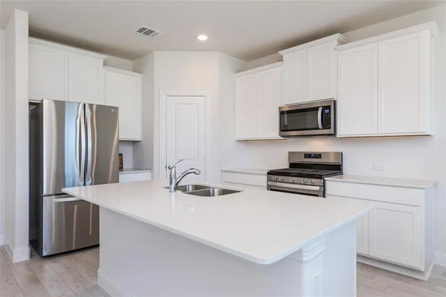 a kitchen with stainless steel appliances a stove microwave and sink